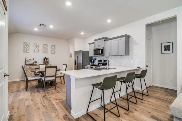 a kitchen with a dining table chairs and wooden floor