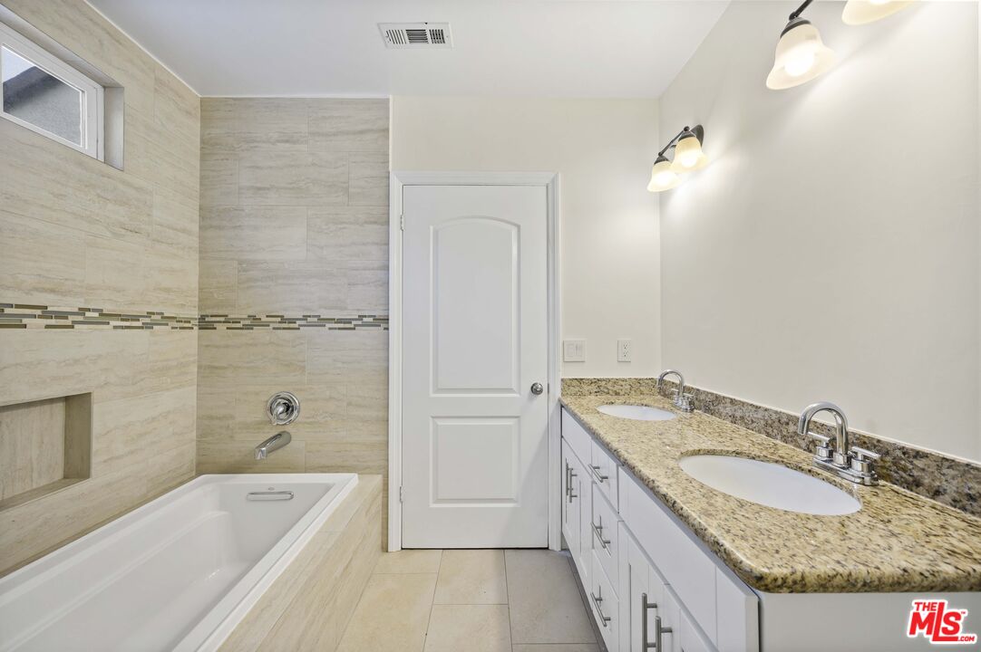 2148 Kelton Avenue Los Angeles, CA 90025 - Photo 18 of 36 a bathroom with a granite countertop tub sink and mirror