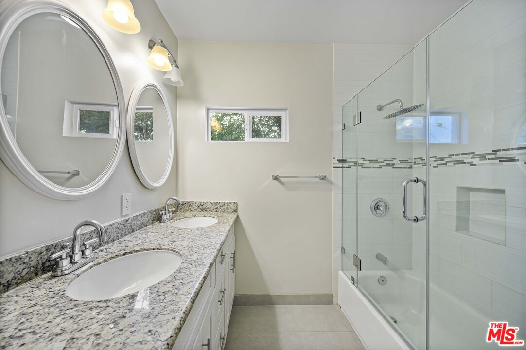 2148 Kelton Avenue Los Angeles, CA 90025 - Photo 21 of 36 a bathroom with a granite countertop double vanity sink a mirror and a shower