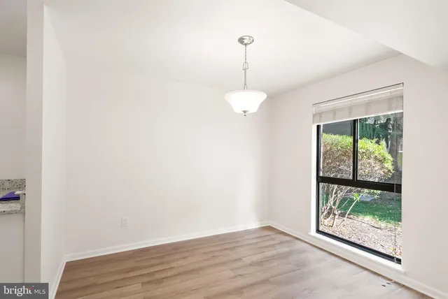 an empty room with wooden floor and fan