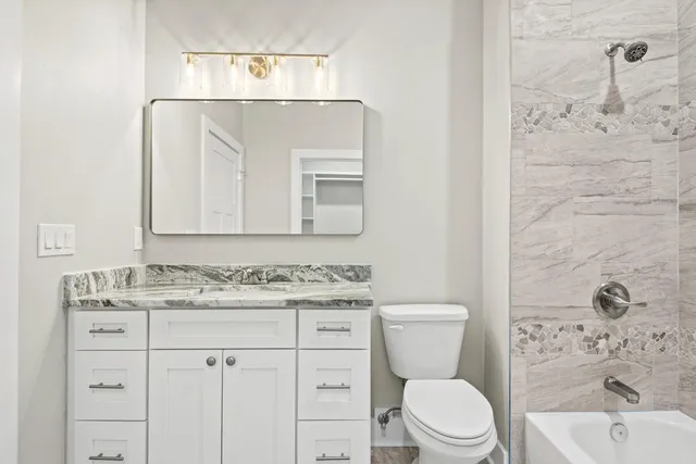 a bathroom with a toilet sink vanity and mirror
