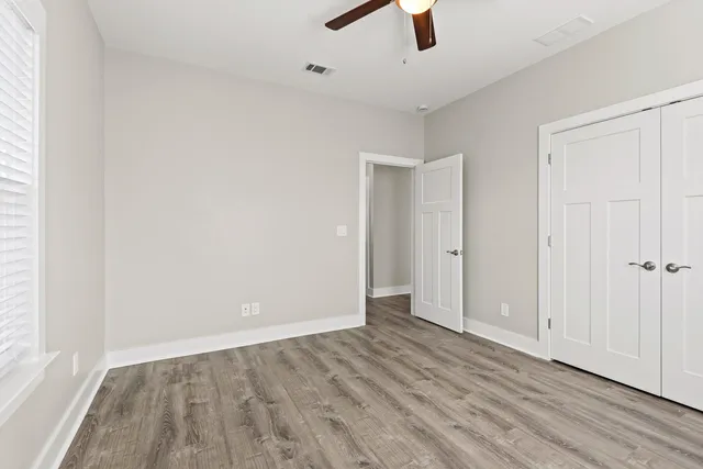 an empty room with ceiling fan and window