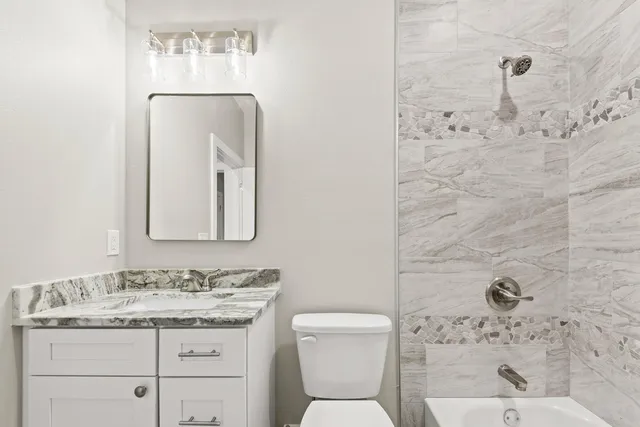 a bathroom with a granite countertop toilet sink and mirror
