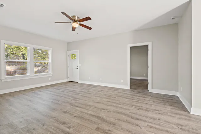 a view of an empty room with wooden floor and a window