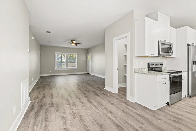 a view of a kitchen with wooden floor and electronic appliances