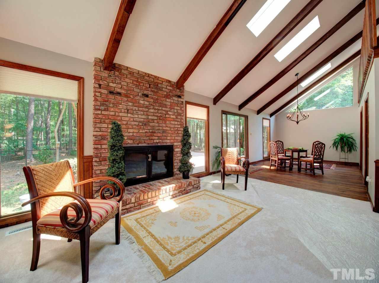 8316 Heel Stone Court Raleigh, NC 27613 - Photo 4 of 25 a living room with furniture a fireplace and floor to ceiling windows