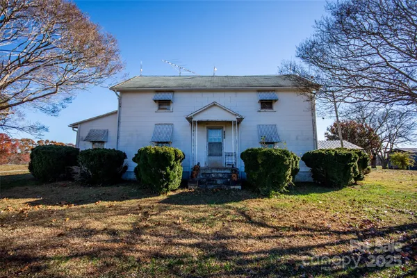 a view of a swimming pool with lawn chairs and large trees