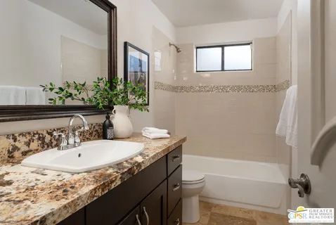 a bathroom with a granite countertop sink a toilet and shower