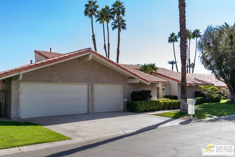 a view of a house with a yard and palm trees