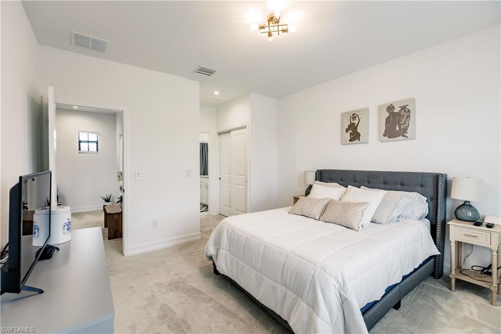 7536 Carnegie Way Naples, FL 34119 - Photo 16 of 23 a bedroom with a bed and a flat tv screen on the dresser