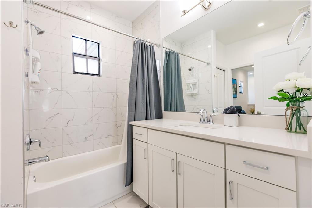 7536 Carnegie Way Naples, FL 34119 - Photo 17 of 23 a bathroom with a granite countertop sink mirror double vanity and bathtub