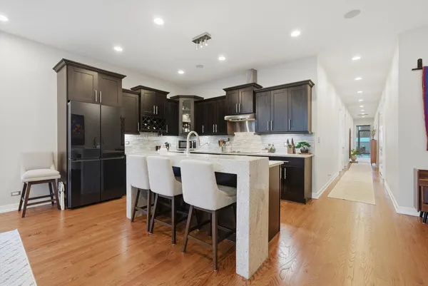 a kitchen with kitchen island granite countertop a center island stainless steel appliances cabinets and wooden floor