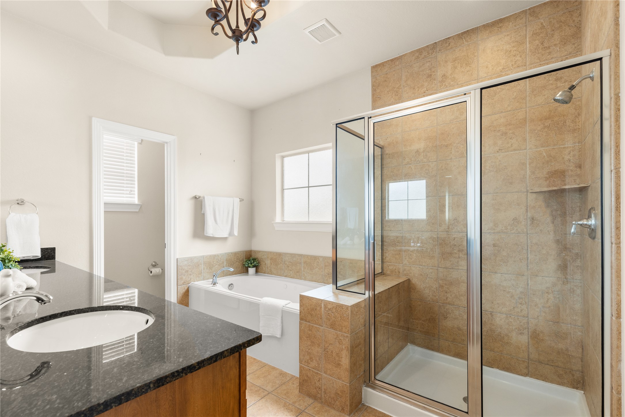 3334 Clearview Villa Way Houston, TX 77025 - Photo 17 of 35 This bathroom features a modern design with a glass-enclosed shower, a separate bathtub, and a granite countertop with double sinks. The neutral tile and ample natural light create a welcoming and clean atmosphere.