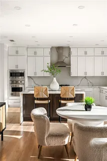 a large white kitchen with stainless steel appliances kitchen island granite countertop a stove a sink and a refrigerator