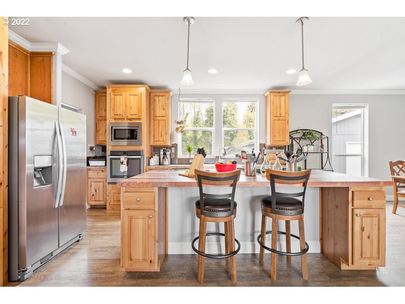 10794 Summit Loop Road Southeast Turner, OR 97392 - Photo 3 of 32 a kitchen with stainless steel appliances kitchen island granite countertop a refrigerator a stove a dining table and chairs with wooden floor