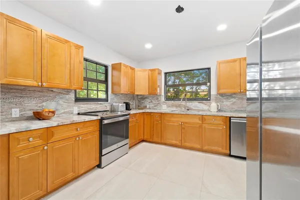 a kitchen with stainless steel appliances granite countertop wooden cabinets a stove top oven a sink and dishwasher
