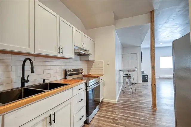 a kitchen with stainless steel appliances a sink cabinets and wooden floor
