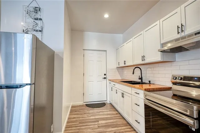 a kitchen with stainless steel appliances a sink dishwasher a refrigerator and cabinets