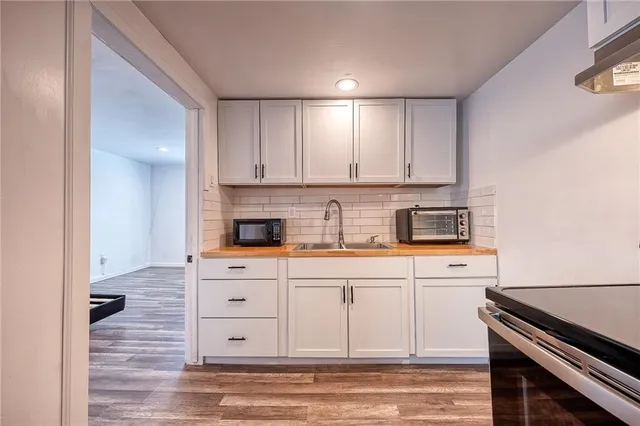 a kitchen with stainless steel appliances white cabinets and a stove top oven