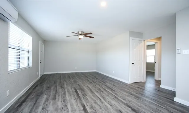 an empty room with wooden floor cabinet and windows