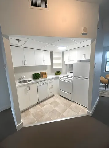 a kitchen with white cabinets and white appliances