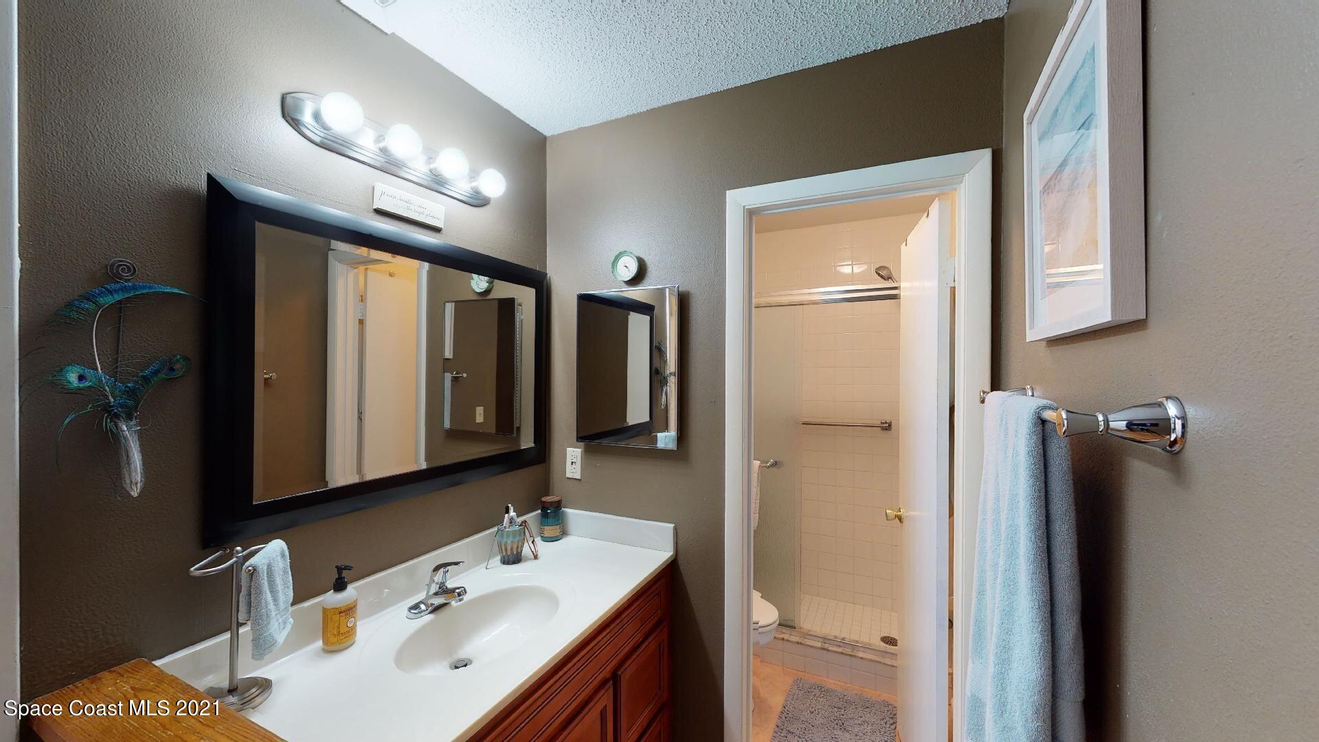 2210 Golf Isle Drive, Unit 906 Melbourne, FL 32935 - Photo 58 of 74 a bathroom with a sink a mirror and a shower