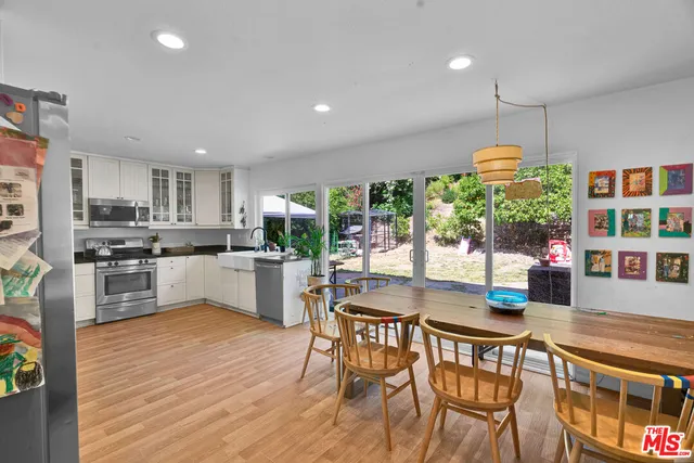 a kitchen with stainless steel appliances granite countertop a stove top oven a sink dishwasher and white cabinets with wooden floor