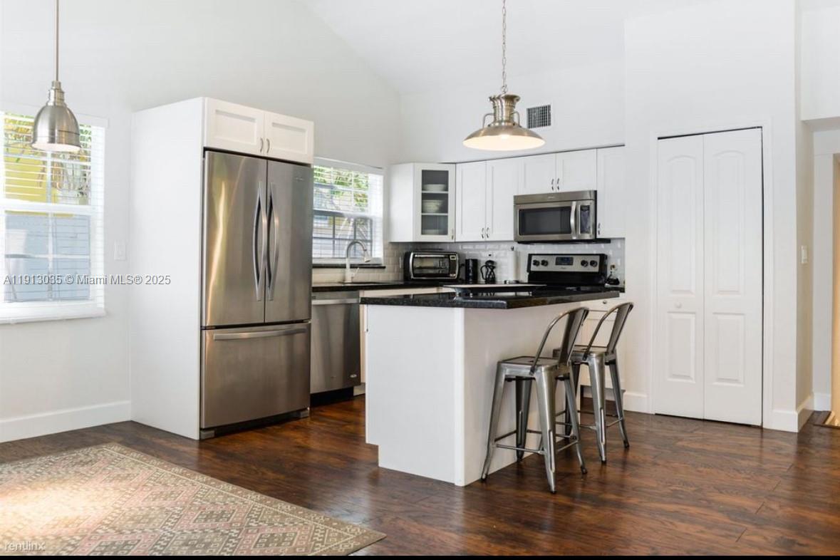 7611 Abbott Avenue, Unit R Miami Beach, FL 33141 - Photo 2 of 10 a kitchen with kitchen island a refrigerator a stove a microwave and cabinets