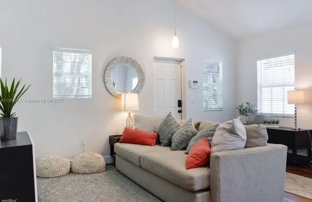 a living room with furniture a large window and a potted plant