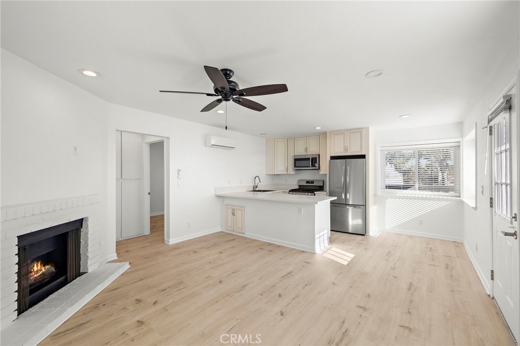 33771 Copper Lantern Street, Unit B Dana Point, CA 92629 - Photo 1 of 14 a large white kitchen with a refrigerator a stove top oven a sink dishwasher and a fireplace