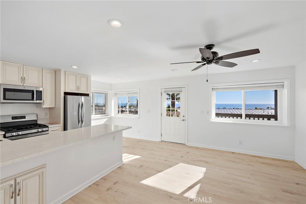 33771 Copper Lantern Street, Unit B Dana Point, CA 92629 - Photo 3 of 14 a kitchen with stainless steel appliances granite countertop a refrigerator a stove top oven a sink a dining table and chairs with wooden floor