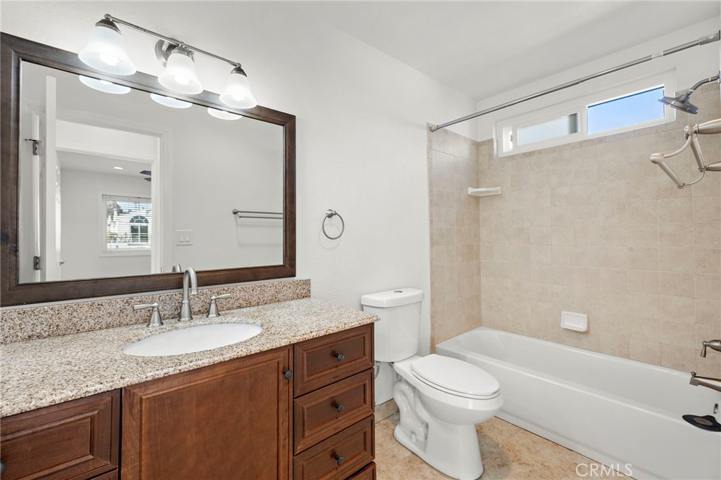 33771 Copper Lantern Street, Unit B Dana Point, CA 92629 - Photo 9 of 14 a bathroom with a granite countertop sink a toilet a mirror a bathtub and shower