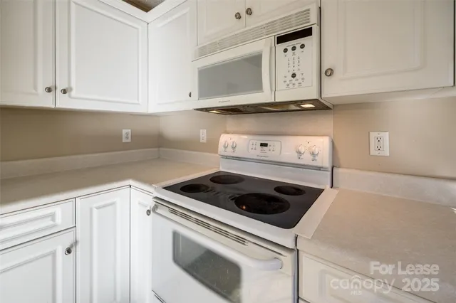 a kitchen with white cabinets and white appliances