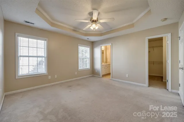 an empty room with chandelier fan and windows