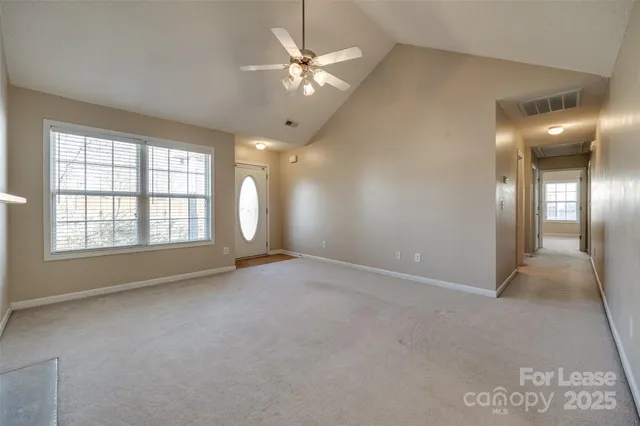 an empty room with windows and chandelier fan