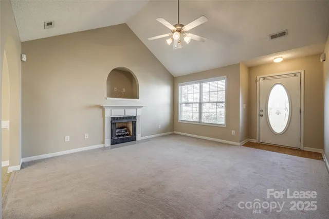an empty room with windows fireplace and fan