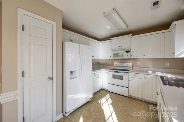 a kitchen with white cabinets and white appliances