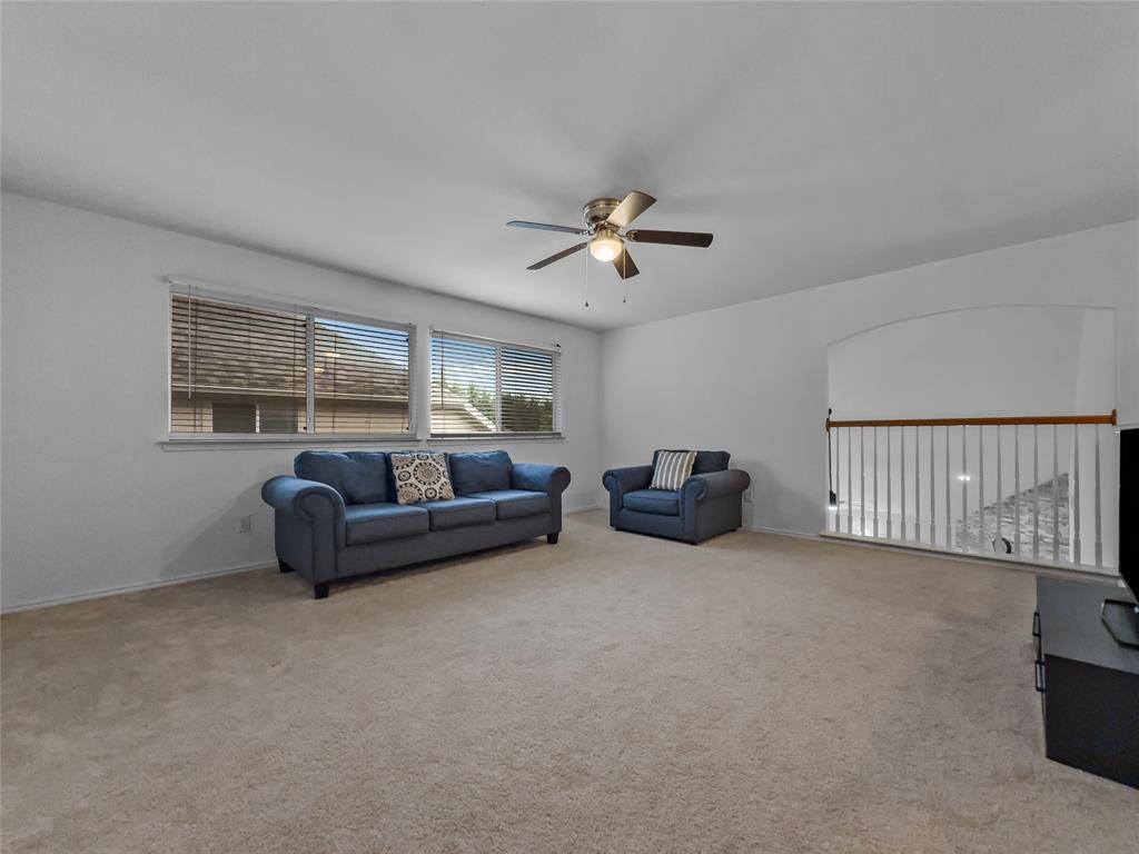 3008 Devlin Ridge Drive Plano, TX 75025 - Photo 17 of 24 Carpeted room featuring multiple windows with blinds, a ceiling fan with integrated lighting, and a white balustrade with a wood handrail