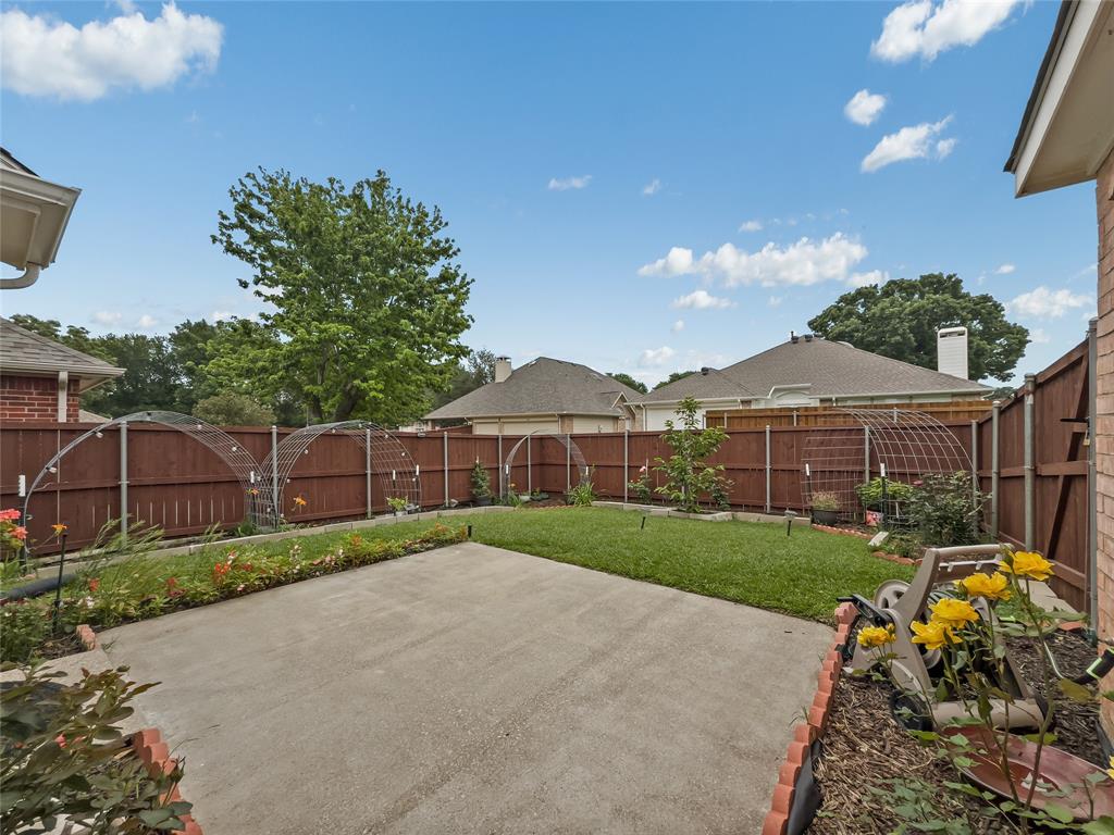 3008 Devlin Ridge Drive Plano, TX 75025 - Photo 19 of 24 Backyard featuring a concrete patio, manicured lawn, perimeter fencing, and established garden beds with various plantings