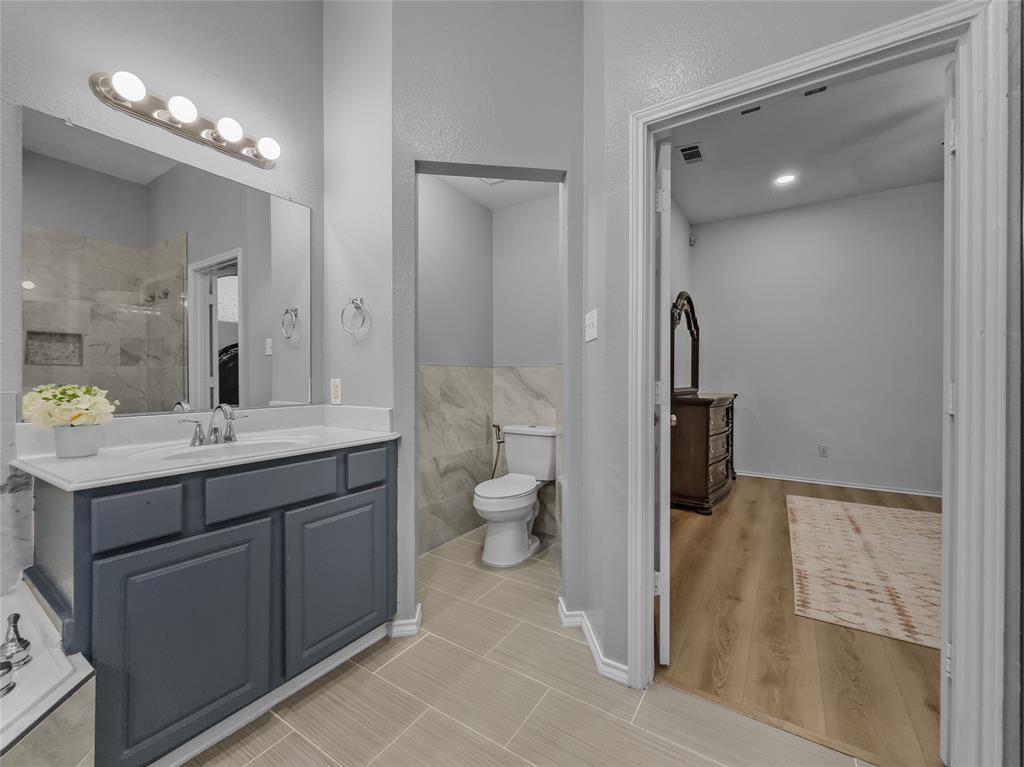 3008 Devlin Ridge Drive Plano, TX 75025 - Photo 22 of 24 Bathroom featuring a gray vanity with a white countertop, chrome faucet, and a large wall-mounted mirror