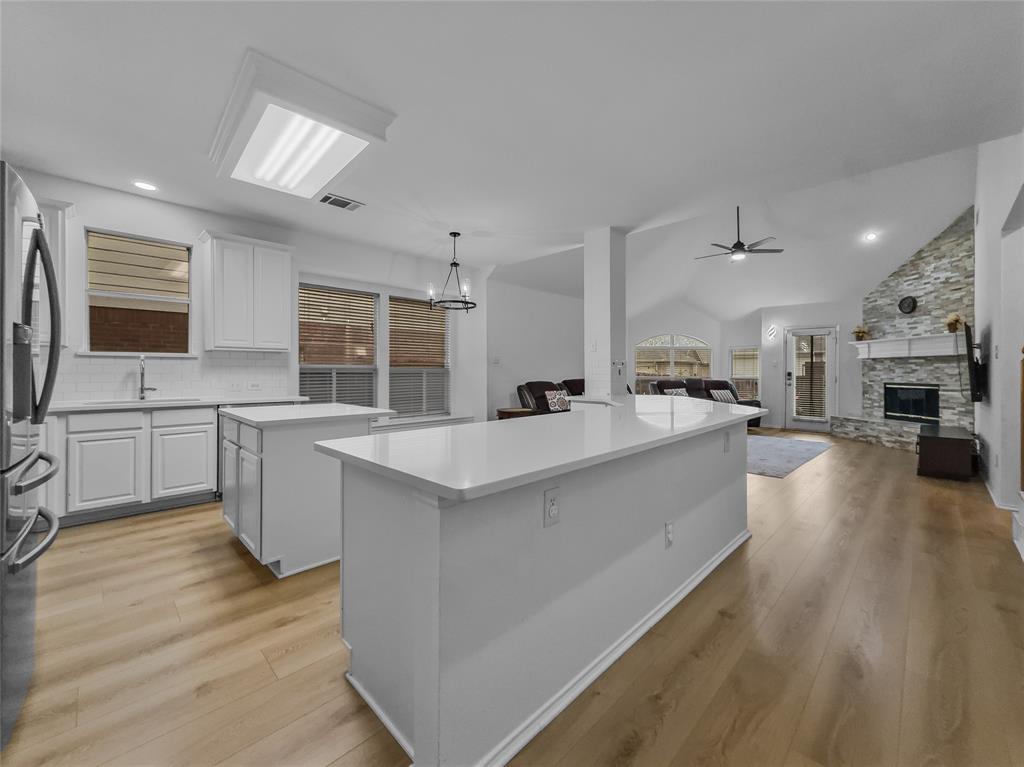3008 Devlin Ridge Drive Plano, TX 75025 - Photo 6 of 24 Open-concept living area featuring a kitchen with two islands, quartz countertops, white cabinetry, and wood-finish flooring