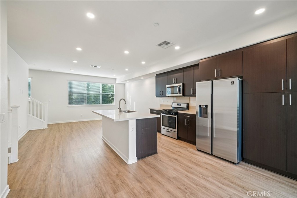 9422 Shade Place Rancho Cucamonga, CA 91730 - Photo 12 of 72 a kitchen with stainless steel appliances a refrigerator and a wooden floor