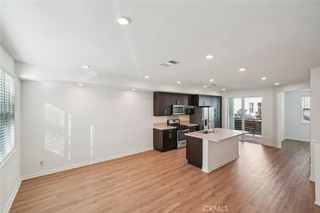 a kitchen with stainless steel appliances granite countertop a refrigerator a stove top oven a sink dishwasher and wooden floor