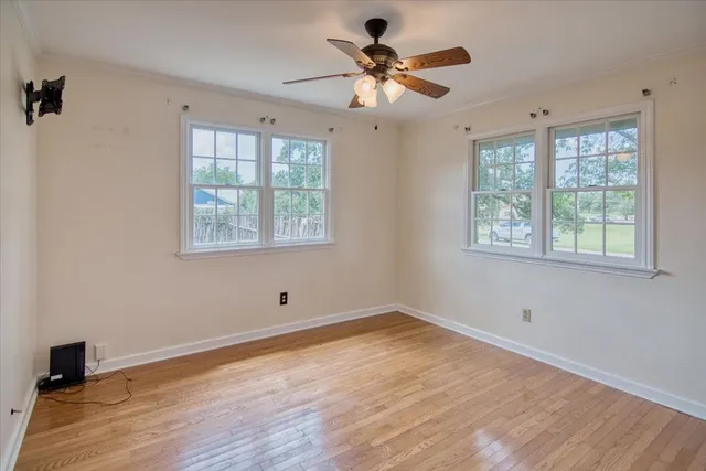 a view of an empty room with wooden floor and a window