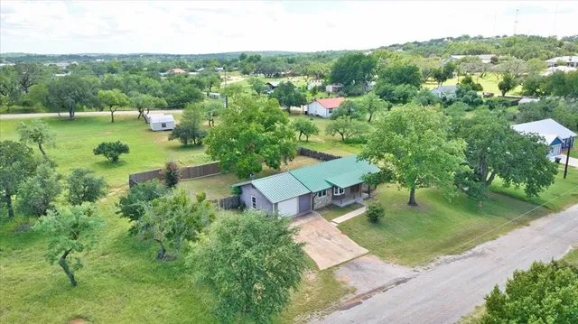 an aerial view of residential houses with outdoor space and trees