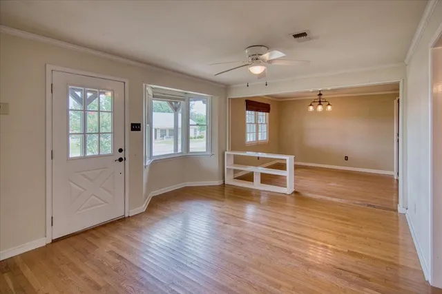 an empty room with wooden floor and windows