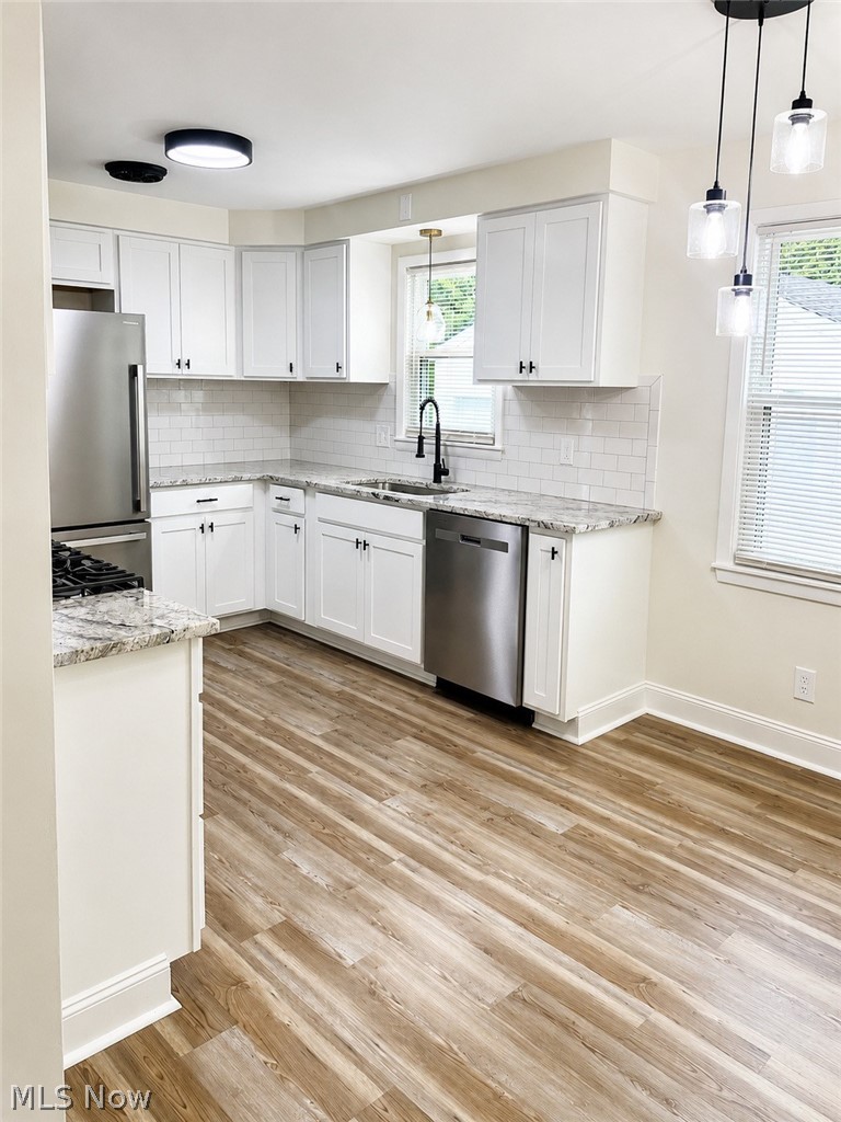 628 Creed Street Struthers, OH 44471 - Photo 4 of 20 Modern kitchen featuring white cabinetry, granite countertops, subway tile backsplash, stainless steel appliances, and wood-finish flooring