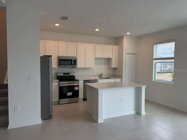 a kitchen with white cabinets and refrigerator