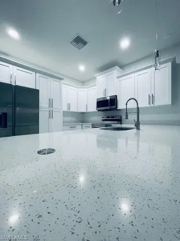 a kitchen with stainless steel appliances granite countertop a stove a sink and a microwave