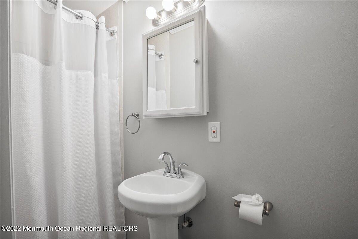 5 Island View Way, Unit 10 Sea Bright, NJ 07760 - Photo 8 of 30 a bathroom with a sink a mirror and a shower curtain